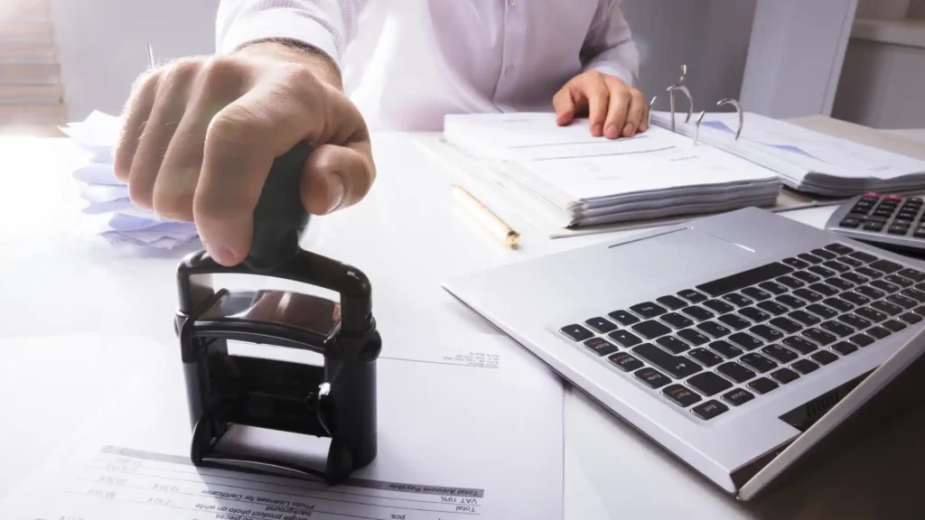 clerk stamping a paper with a laptop on the desk