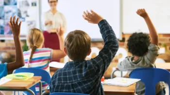 classroom of kids raising their hands