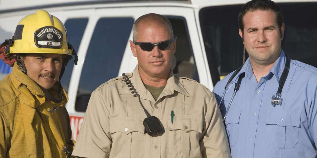 photograph of a firefighter, law enforcement officer, and medical professional in front of a van