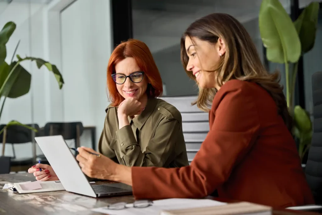 two women looking at a laptop computer in an office